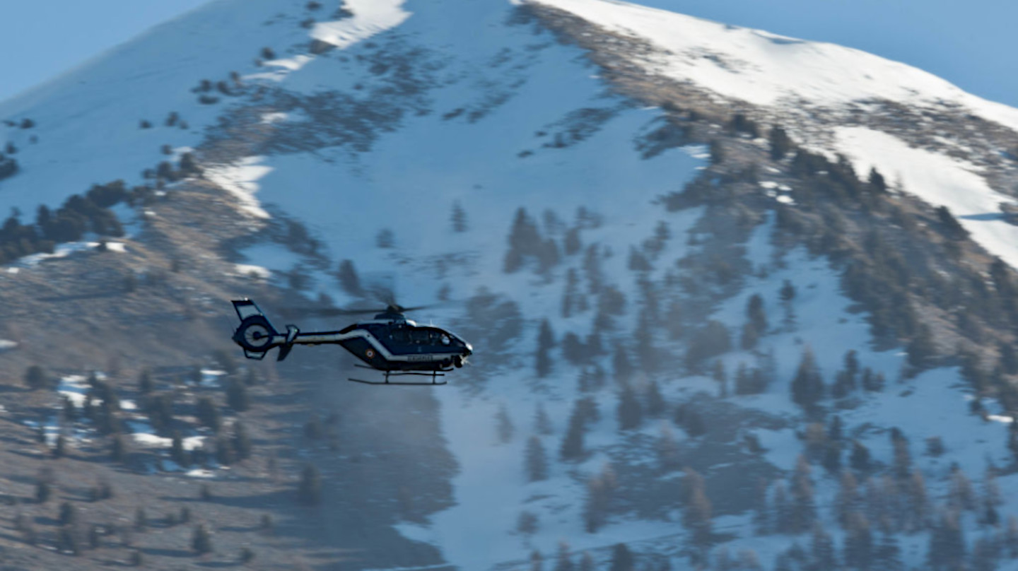 Un hélicoptère survole une zone montagneuse enneigée