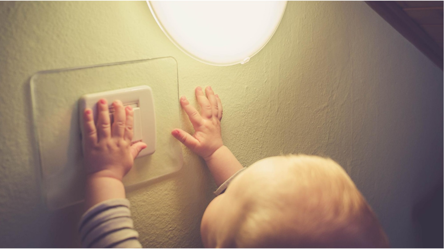 Un jeune enfant la main sur l'interrupteur.