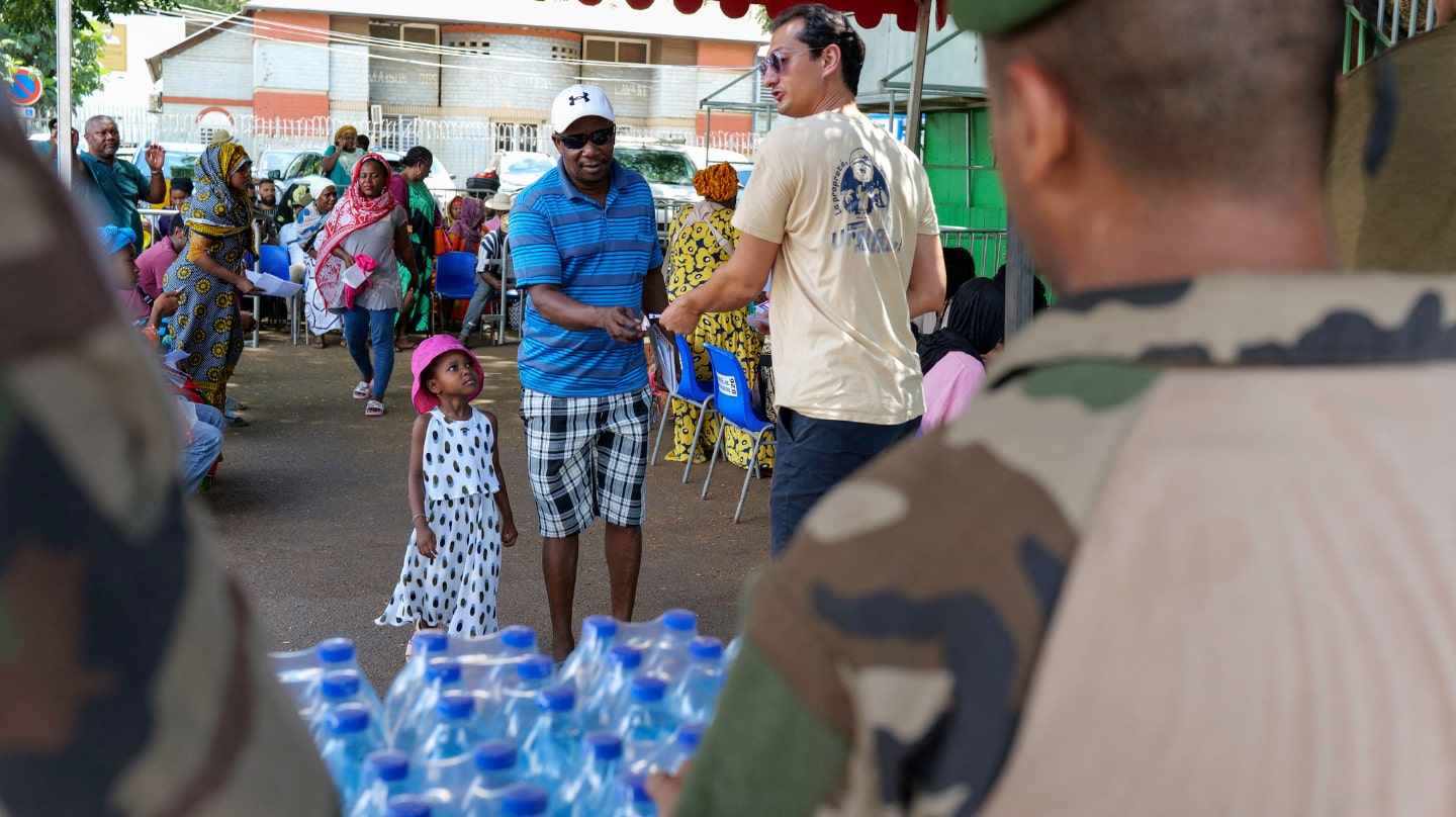 Un homme et une petite fille viennent récupérer des bouteilles d'eau distribuées à Mayotte.