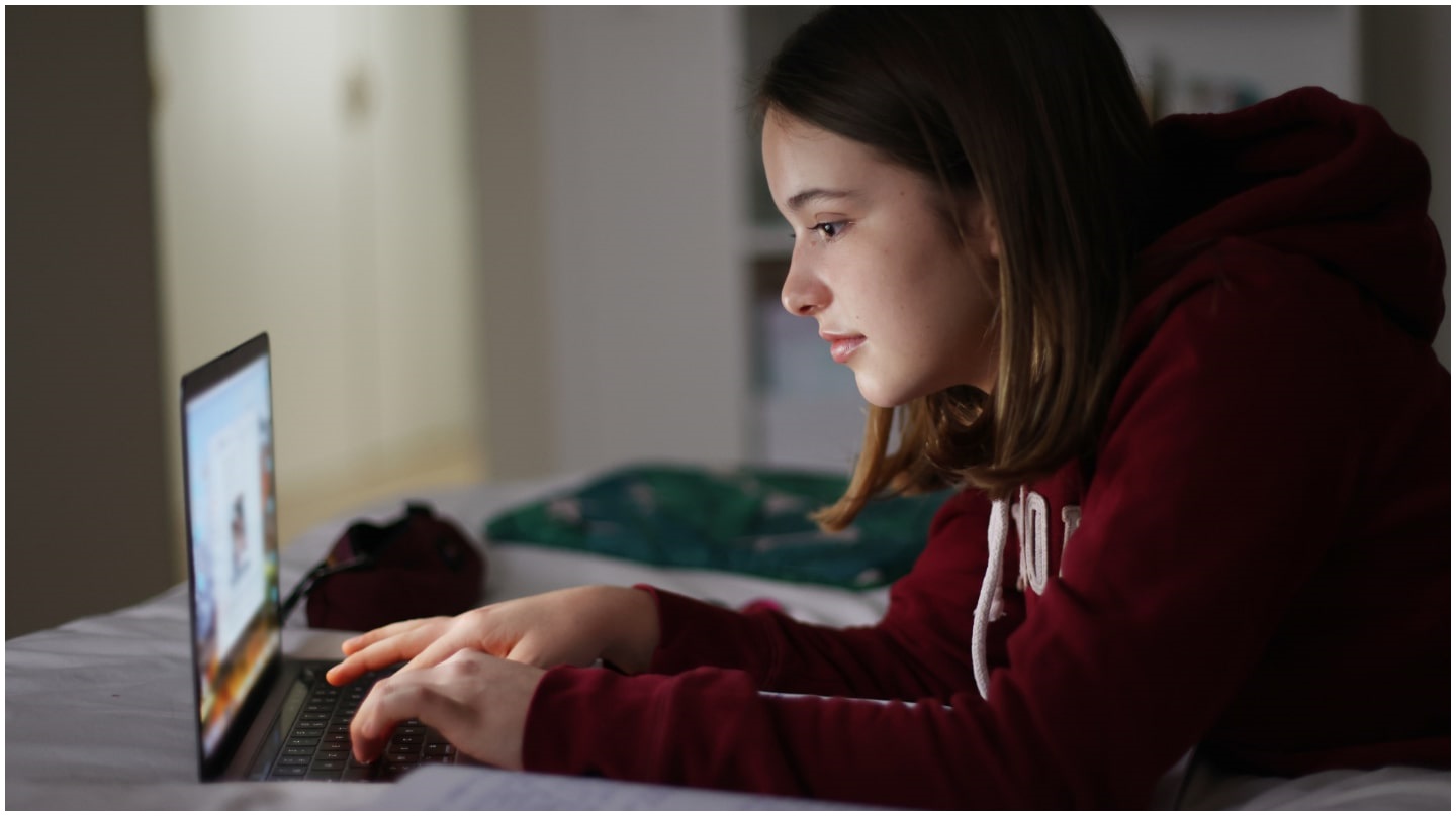 Une jeune fille consulte son ordinateur portable.