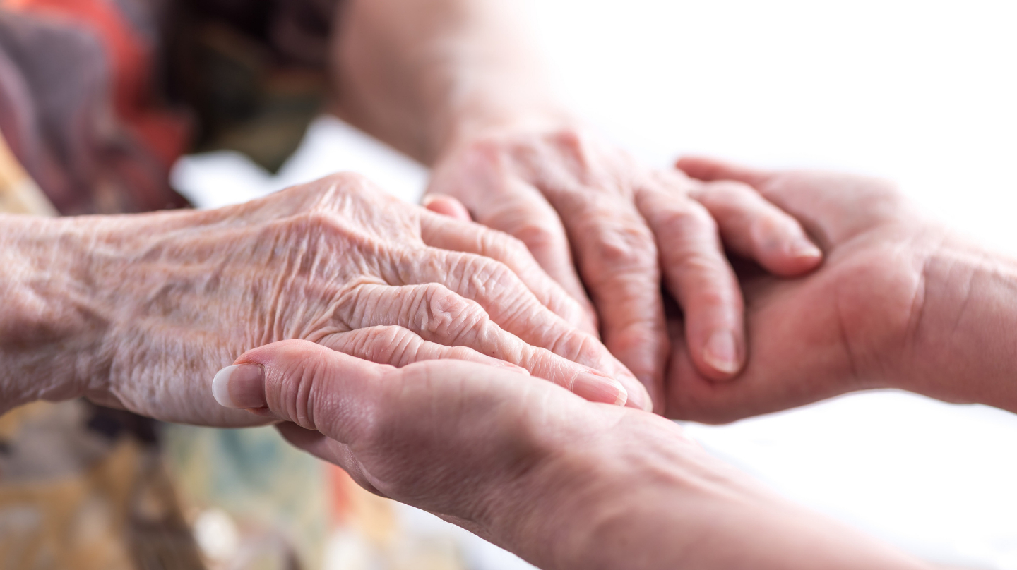 Une personne tient les mains d'une personne plus âgée dans les siennes.