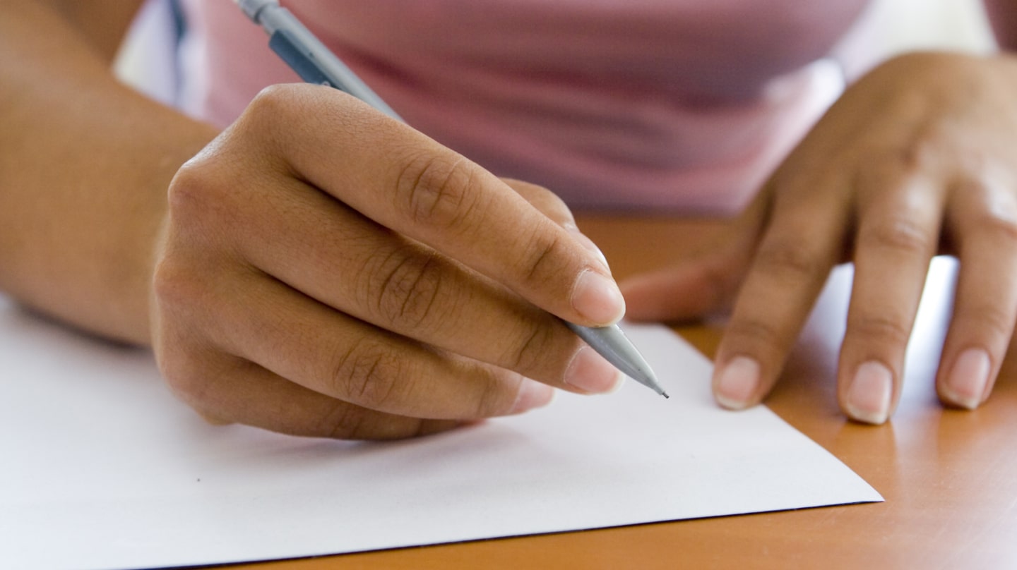 Un gros plan sur des mains s'apprêtant à écrire à l'aide d'un crayon.