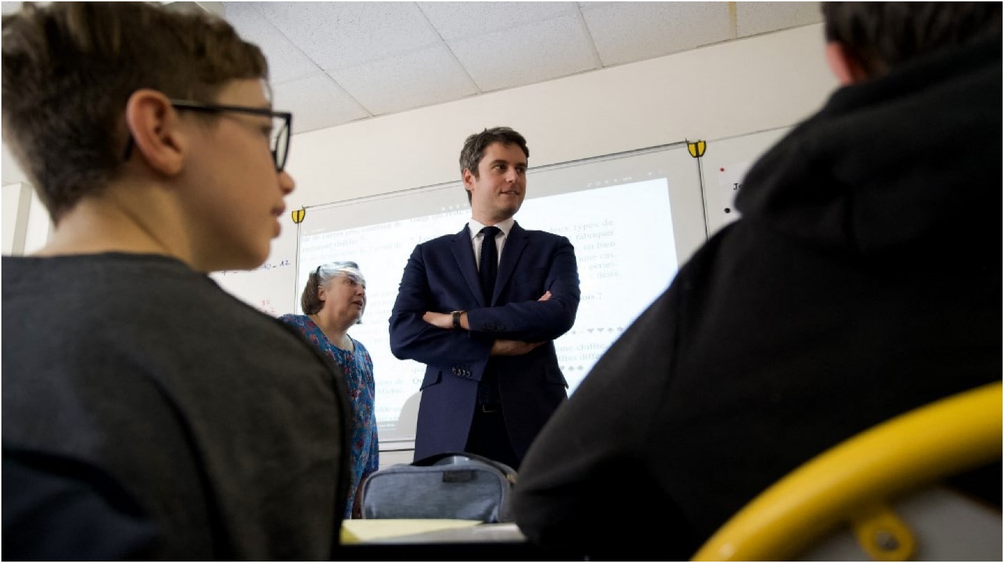 Le Premier ministre dans une salle de classe, des élèves de dos au premier plan.