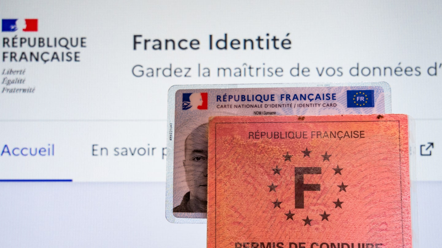Deux permis de conduire, ancien et nouveau format, devant un écran d'ordinateur affichant France identité.