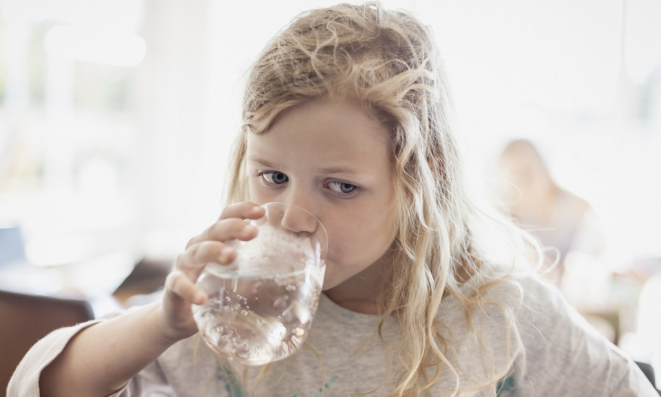 Une fillette boit un verre d'eau